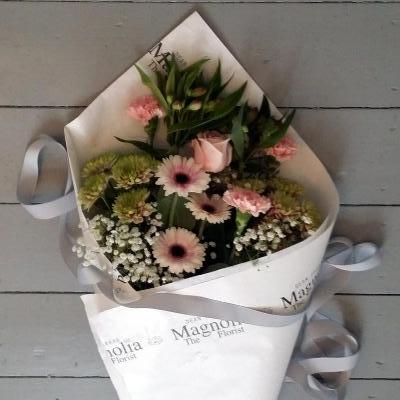 Dover Gift Wrapped Bouquet - Magnolia the Florist The Dover Bouquet, from Magnolia the Florist, is a traditional wrapped style presentation. Featuring a stunning mix of pink-toned flowers with a hint of green. Please note that flower selection may vary based on availability but would normally include roses, alstroemeria, mini gerbera, chrysanthemums, carnations, and gyp. This bouquet is sure to make a beautiful statement.