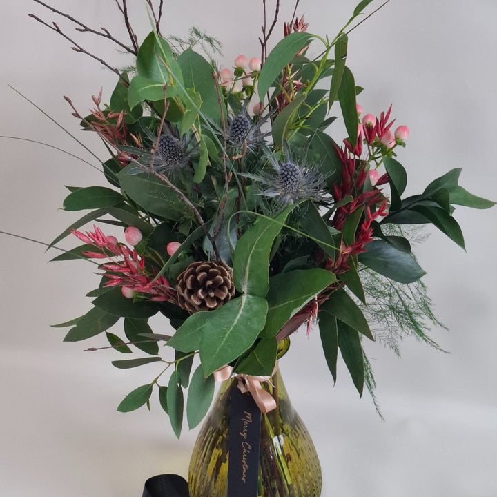 Bouquet of foilage in a green vase against a plain background