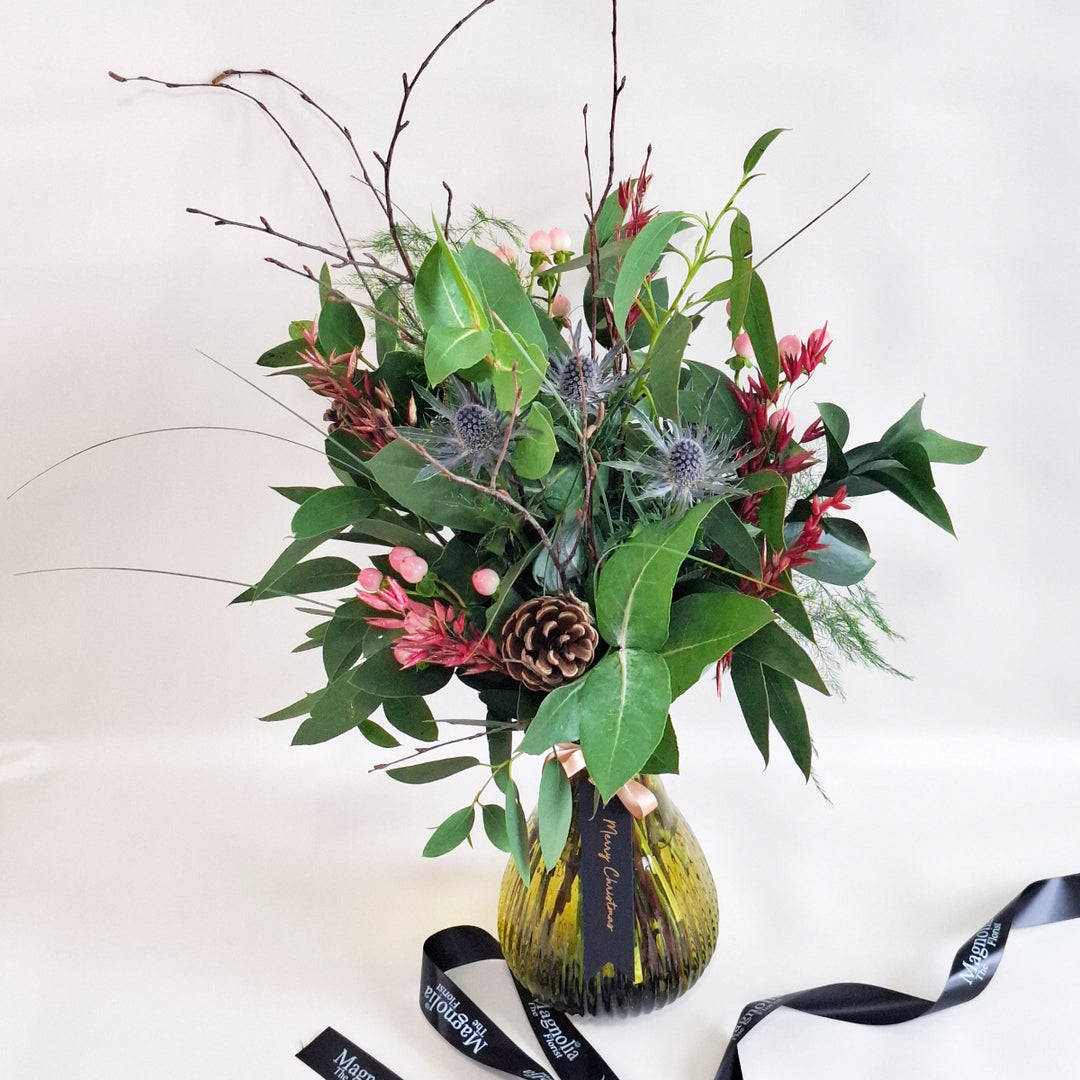 Bouquet of foilage in a green vase against a plain background