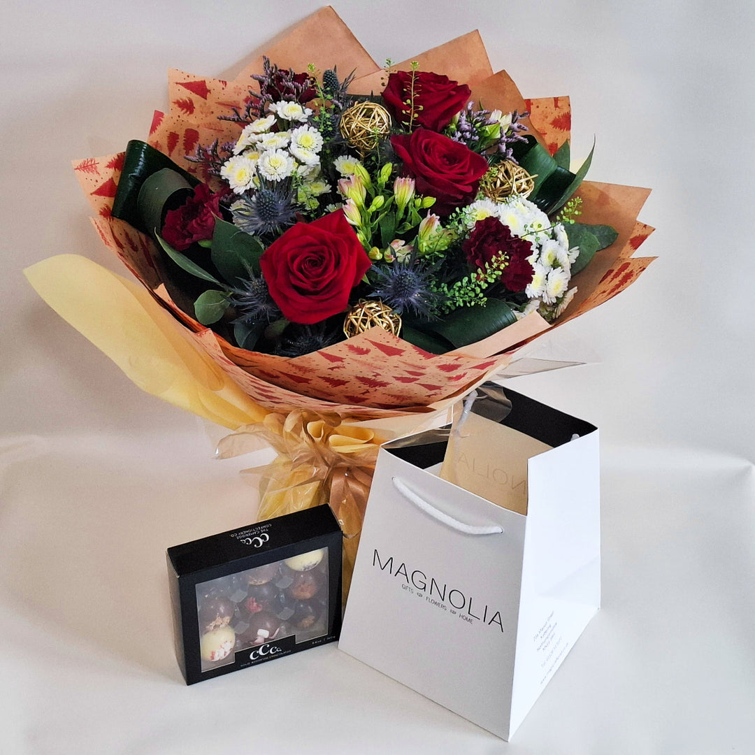 Bouquet of flowers with a box and a white bag labeled 'Magnolia' on a light background