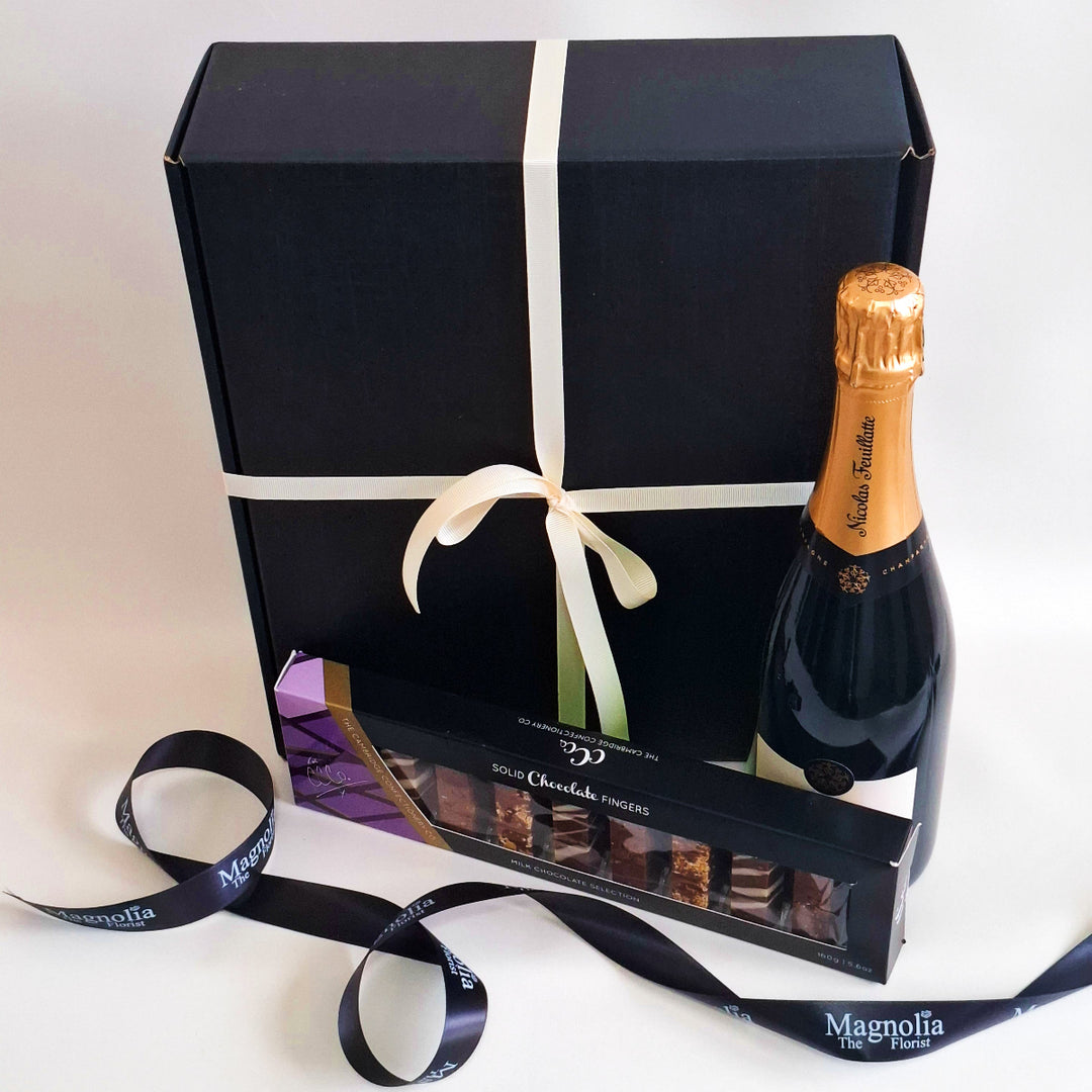 Gift set with champagne bottle and chocolates in a black box with white ribbon