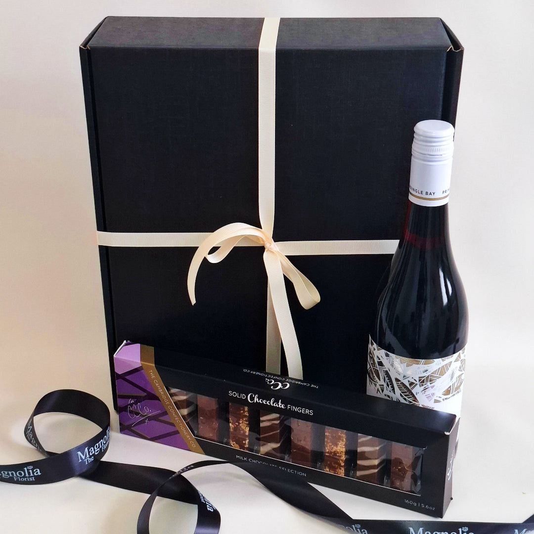 Bottle of red wine and box of chocolates with a black gift box on a white background