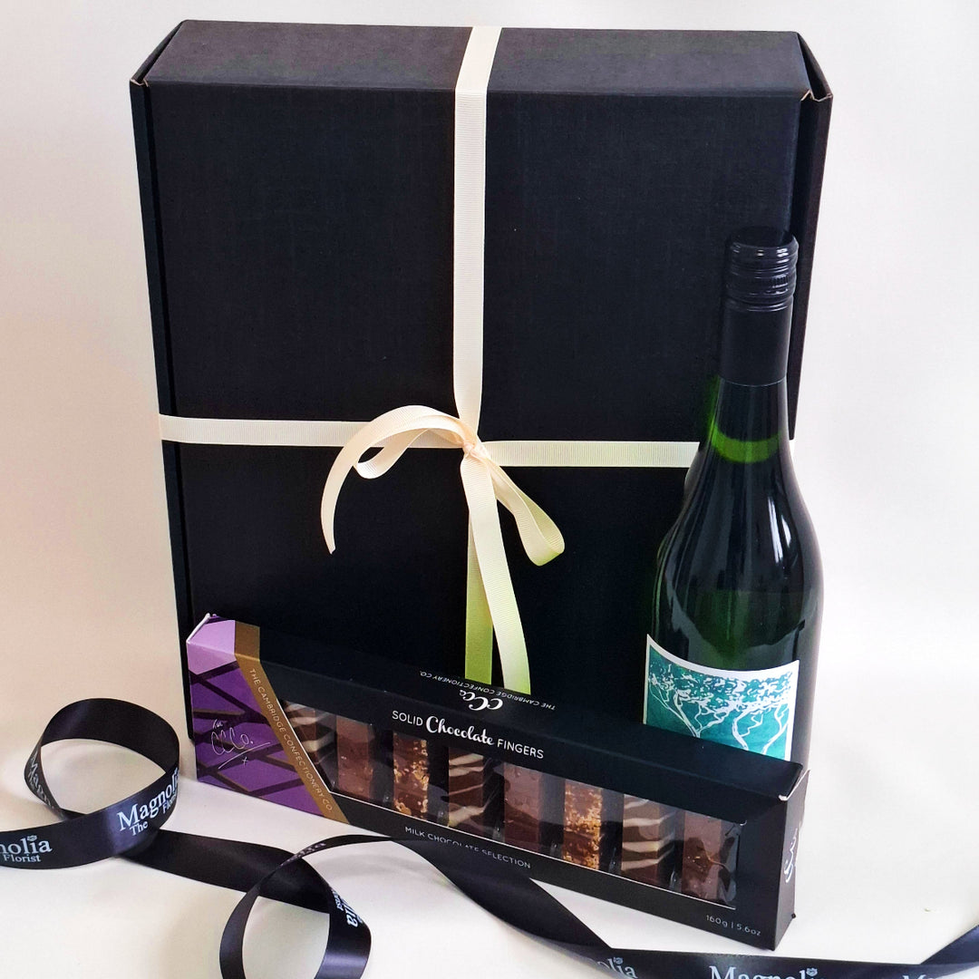 White wine bottle with a box of chocolates and a black gift box