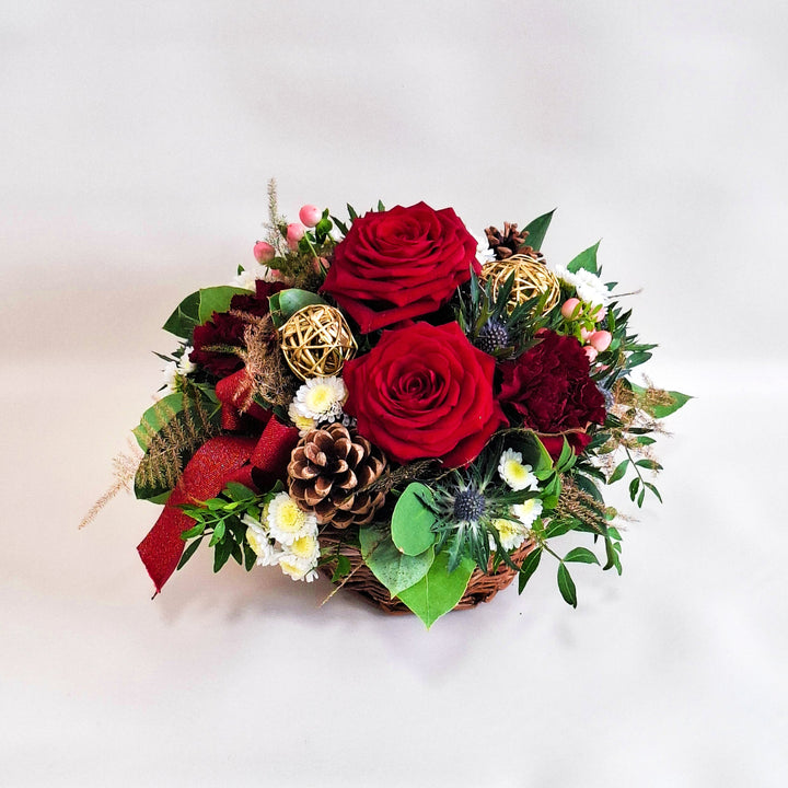 Arrangement of red roses, pinecones, and greenery in a wicker basket