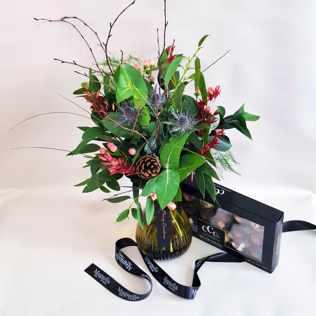 Bouquet of flowers in a vase with a box of chocolates on a white background