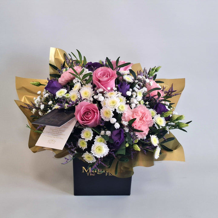 Petite Highgrove Arrangement - Magnolia the Florist Highgrove is a soft, romantic floral arrangement crafted with pink roses, pink carnations, white chrysanthemum, purple lisianthus, limonium, gyp and pistache. Presented in our Magnolia‑branded box and arranged in floral foam for long‑lasting freshness. For scale purposes, our branded box is 15cm (h) x 12cm (w) x 12cm (d), giving an overall size of approximately 25cm (h) x 18cm (w).  3