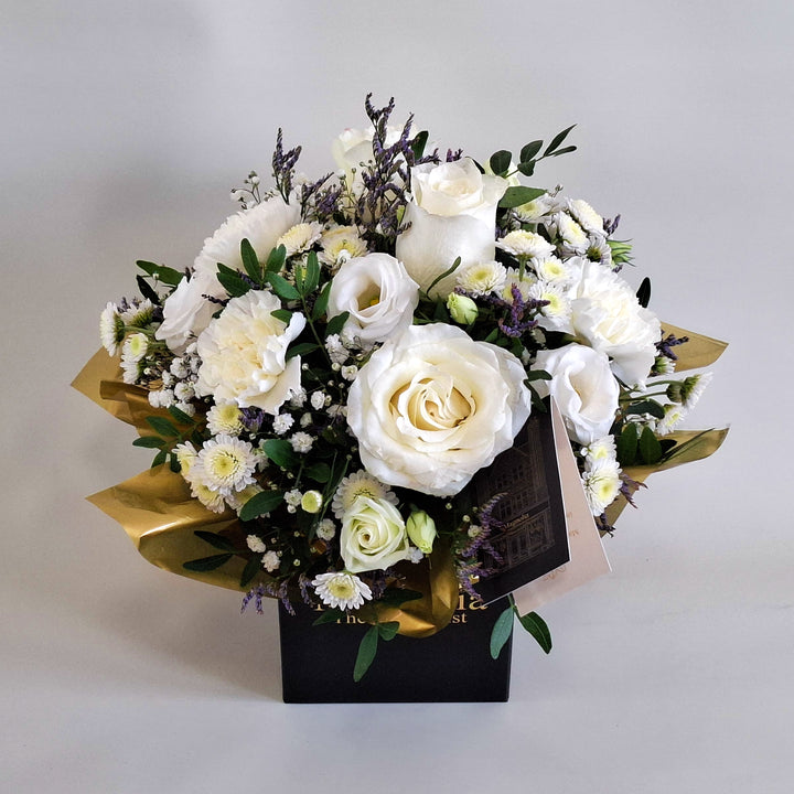 Dainty Kew Arrangement - Magnolia the Florist Kew is a serene all‑white floral arrangement inspired by botanical elegance. Featuring white roses, white carnations, white chrysanthemum, white lisianthus, limonium, gyp and pistache. Presented in our Magnolia‑branded box and arranged in floral foam for long‑lasting freshness. For scale purposes, our branded box is 15cm (h) x 12cm (w) x 12cm (d), giving an overall size of approximately 25cm (h) x 18cm (w).  3